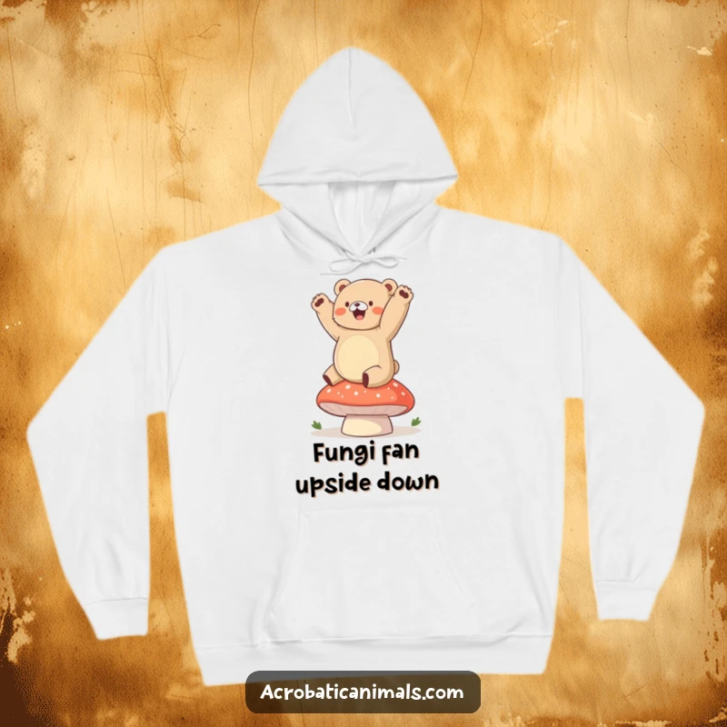 Funny bear hoodie depicting a chubby cub gleefully attempting a handstand on a plump mushroom, wonderfully amusing.