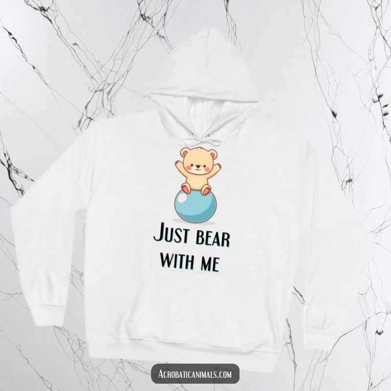 Cozy funny hoodie showcasing a cute bear cub attempting to balance on a large yoga ball, a humorous and warm design.